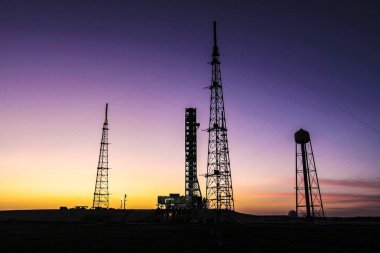 Florida 'daki Nasas Kennedy Uzay Merkezi' nin arka planında güneş batarken mobil fırlatıcı fırlatma rampasına doğru 4.2 millik yolculuğunu tamamlamak üzere. Bu görüntünün unsurları Nasa tarafından desteklenmektedir