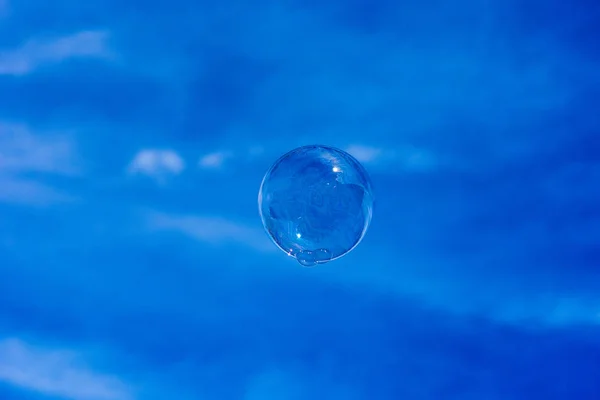 Soap bubbles blowing up in blue sky