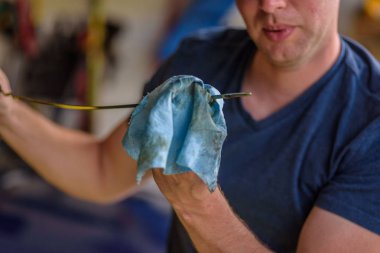 Adam yağ seviyesini dipstick 'te kontrol ediyor