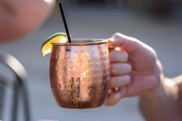 man holding a Moscow Mule in bright copper mug