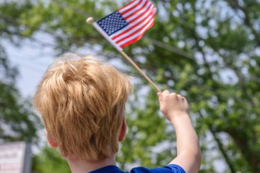 4 Temmuz geçit töreninde Amerikan bayrağı sallayan küçük çocuk.