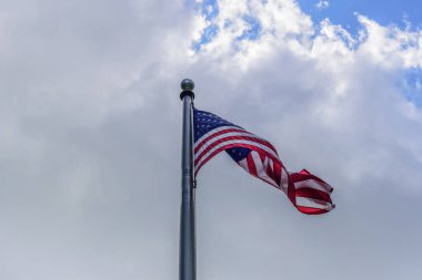 Amerikan bayrağının bayrak direğine bulutlar ve gökyüzü üzerinde sallayarak düşük açılı görünüş