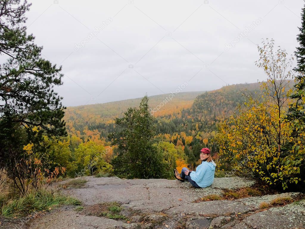 woman looking out at beautiful fall colors from top of Oberg Mountain in Minnesota along Superior Hiking Trail