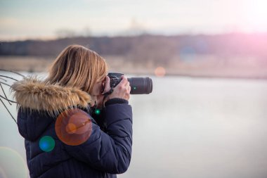 Doğa fotoğrafçısı zoom lensli profesyonel dslr kamera tutuyor
