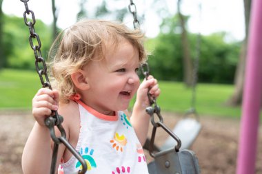 Mutlu çocuk bir yaz günü parkta salıncakta sallanıyor.