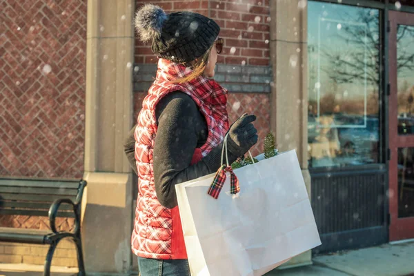 happy woman shopping at outdoor mall holding bags during holiday Christmas season