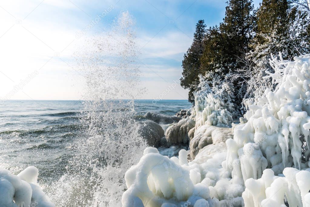 waves crashing on ice covered shoreline at Cave Point Park Door County Wisconsin in winter