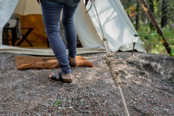 ground level view of woman setting up canvas tent on campsite