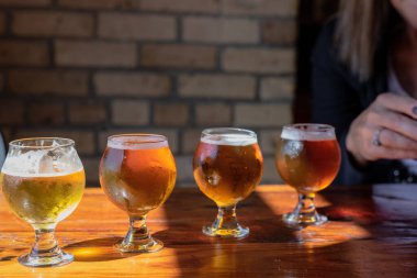 Bira fabrikasındaki ahşap masanın üzerinde el yapımı bira örnekleri.