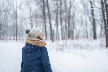 Kadın kış ormanlarında yürürken kar yağıyordu.