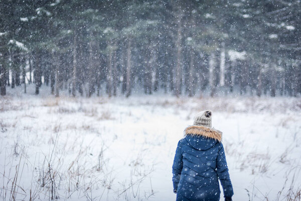 woman walking in blizzard in winter woods