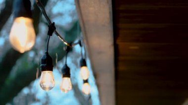 Verandada Edison tarzı parti ışıklarından düşen yağmur damlaları