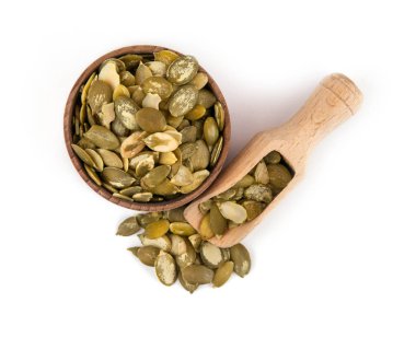 Beyaz bir arka plan üzerine bir kepçe ile ahşap bir kase kabak çekirdeği.