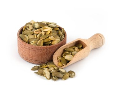 Beyaz bir arka plan üzerine bir kepçe ile ahşap bir kase kabak çekirdeği.