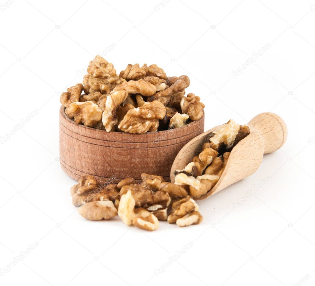 Walnut in a wooden bowl with a scoop on a white background.