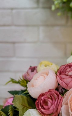 Yapay çiçek buketi. Beyaz tuğla duvarlı şık çiçekçi dükkanında bir buket karışık çiçek..