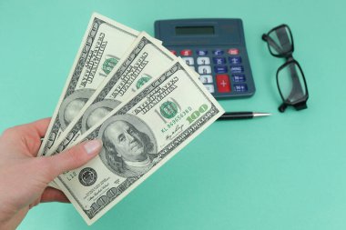 Para, Amerikan banknotları yakın plan, yeşil zemin üzerindeki hesap makinesi ve gözlükler para kavramı, kazanç, vergiler, iki kez ödeme.