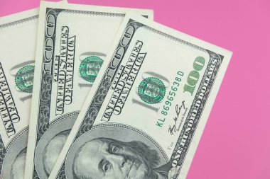 Para ve Amerikan banknotları pembe arka planda kapanıyor.