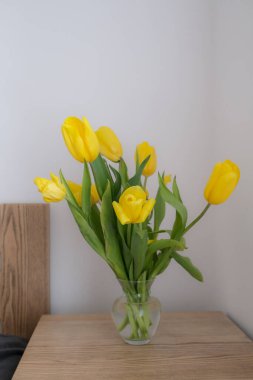 Sarı lale buketi komodinin üzerinde. Çiçek ve hediye vermek ve almak kavramı..