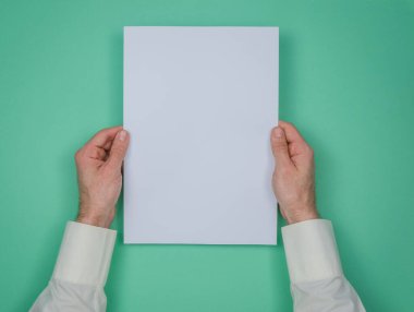 İnsanlar yeşil arka planda beyaz bir kağıt tutuyorlar. Bir metin için yer.