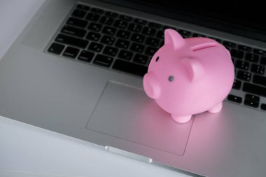 Dizüstü bilgisayarlı pembe kumbara. Tasarruf kavramı, mevduat. Tasarruf etmek için para..