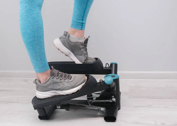 Feet of woman exercising on a twister  stepper. Digital display, keeping fit at home.