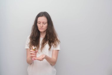 El antiseptiği tutan genç bir kız, gri bir arka planda dezenfektan.. 