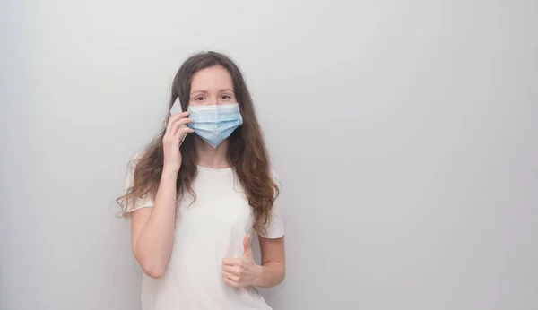 Girl wearing medicine mask talking on the phone with relatives during quarantine, covid-19, corona virus.