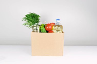 Bağış kutusunda yiyecek, yağ, elma, salatalık, domates ve konserve yiyecek var..