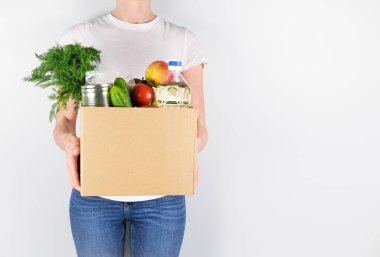 Gri arka planda bağışları olan bir kutu tutan genç kız.. 