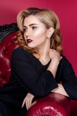 Kırmızı dudaklar kırmızı bir sandalyede oturan bir kırmızı zemin üzerine siyah elbiseli güzel kız