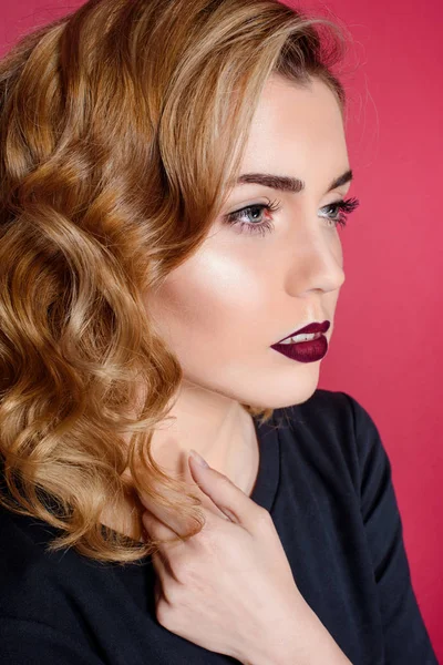 Hermosa chica en un vestido negro sobre un fondo rojo con labios rojos sentado en una silla roja — Foto de Stock