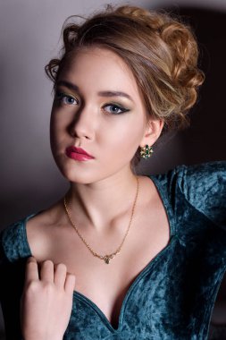 vasıl belgili tanımlık güzel altın koltuk takı göstermek gri bir arka plan üzerinde Yeşil kadife elbiseli güzel kız