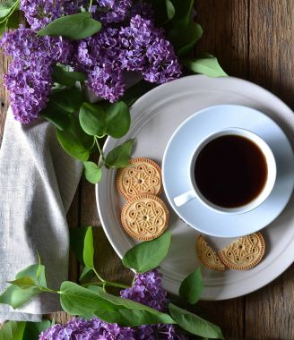Masaya kahve, bisküvi ve eflatun çiçek.