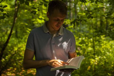 Genç bir adam bir yaz parkta bir kitap okuyor