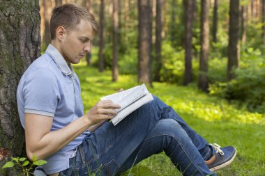 Genç bir adam bir yaz parkta bir kitap okuyor