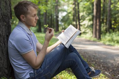 Genç bir adam bir yaz parkta bir kitap okuyor