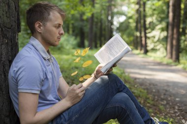 Genç bir adam bir yaz parkta bir kitap okuyor