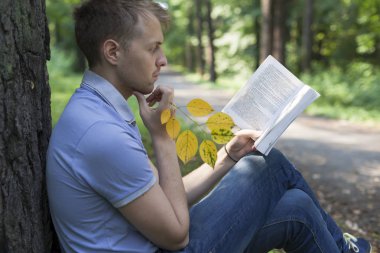 Genç bir adam bir yaz parkta bir kitap okuyor