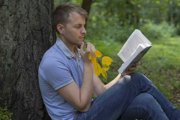 Genç bir adam bir yaz parkta bir kitap okuyor