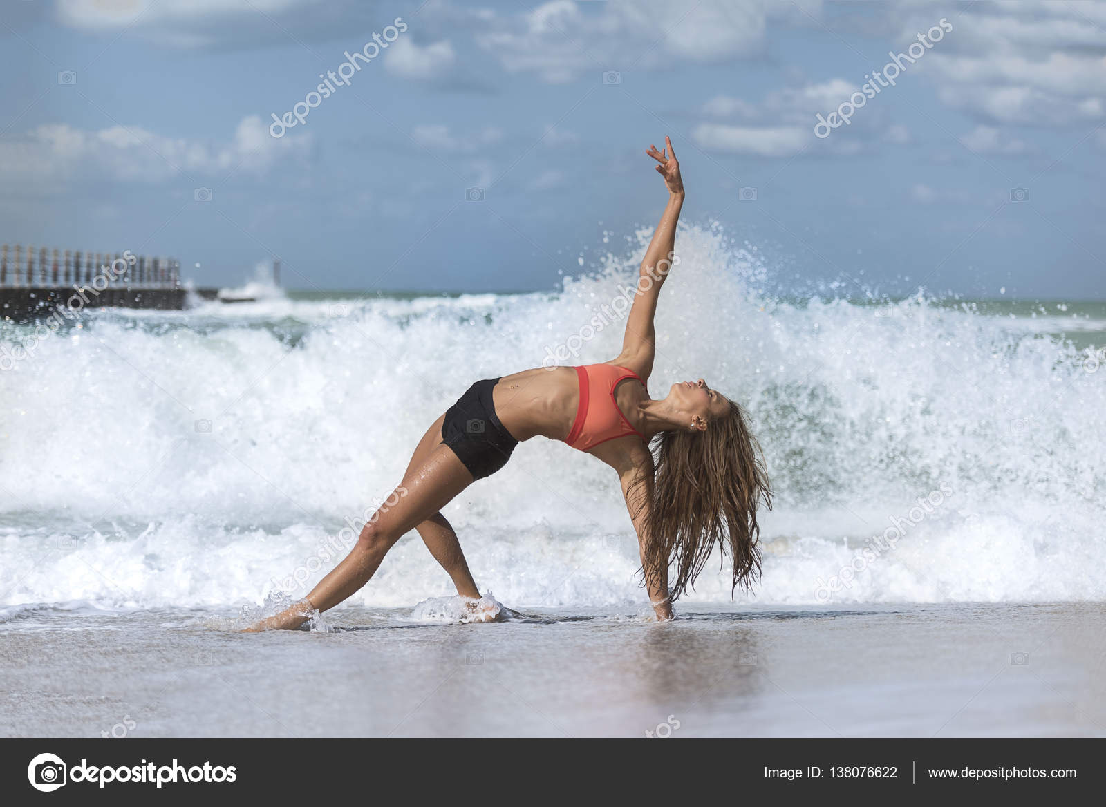Girl in yoga pose with waves crashing over her legs on beach Stock Photo by  ©paiken 138076622
