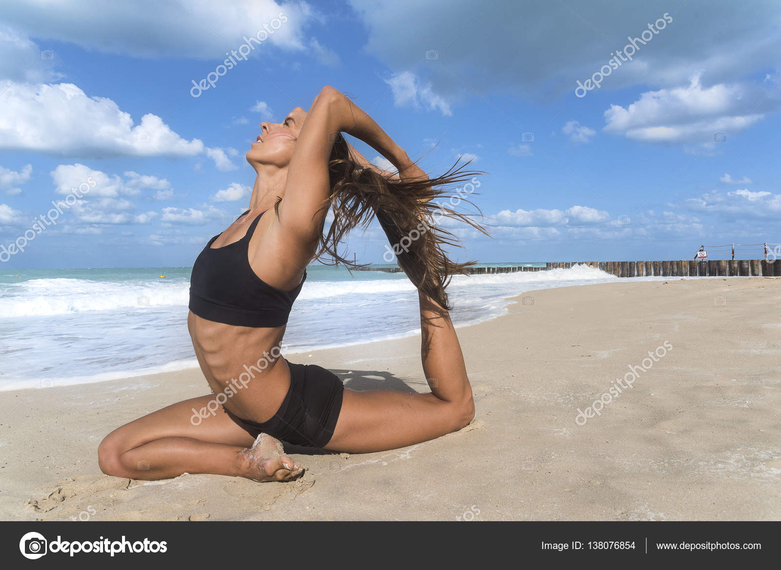 White European girl in a yoga pose on beach with black tight