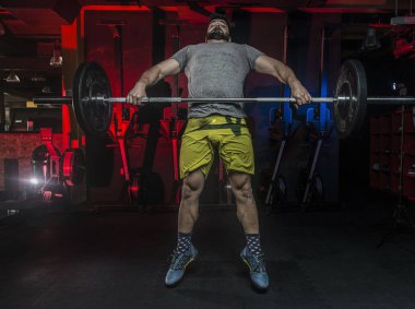 Güçlü beyaz adam bir asansör crossfit kutusunda kırmızı ve mavi aydınlatma içinde jimnastik salonu ile gerçekleştirme 