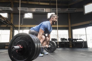 Güçlü beyaz adam deadlift ile agresif bir çığlık çapraz-fit spor salonunda