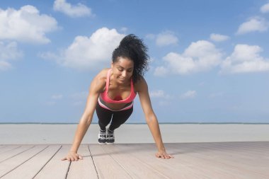 Karışık yarış kız push-up gülümseyen güneşli mavi gökyüzü gün plajda yapıyor