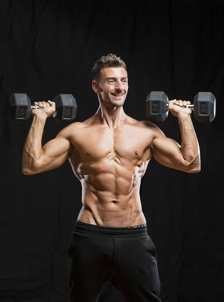 Muscular fisiculturista segurando pesos halteres — Fotografia de Stock