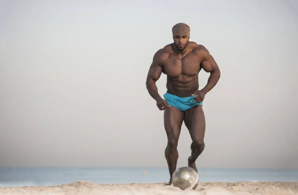 Человек бегает с мячом на пляже — стоковое фото