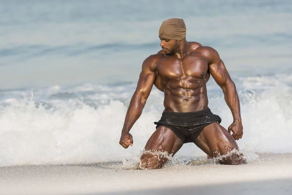 Mann kniet auf nassem Sand am Strand — Stockfoto