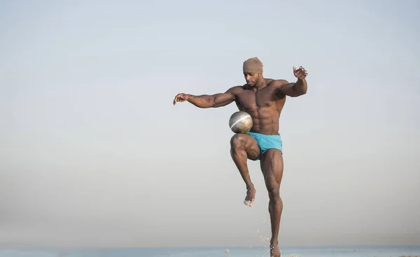 Uomo calci palla sulla spiaggia — Foto Stock