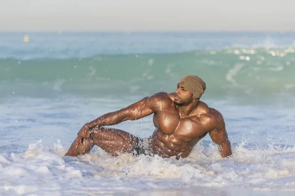 Mann sitzt im Wasser am Rande des Strandes — Stockfoto